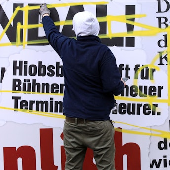 Ein Künstler gestaltet den Frustzaun an der Oper um.