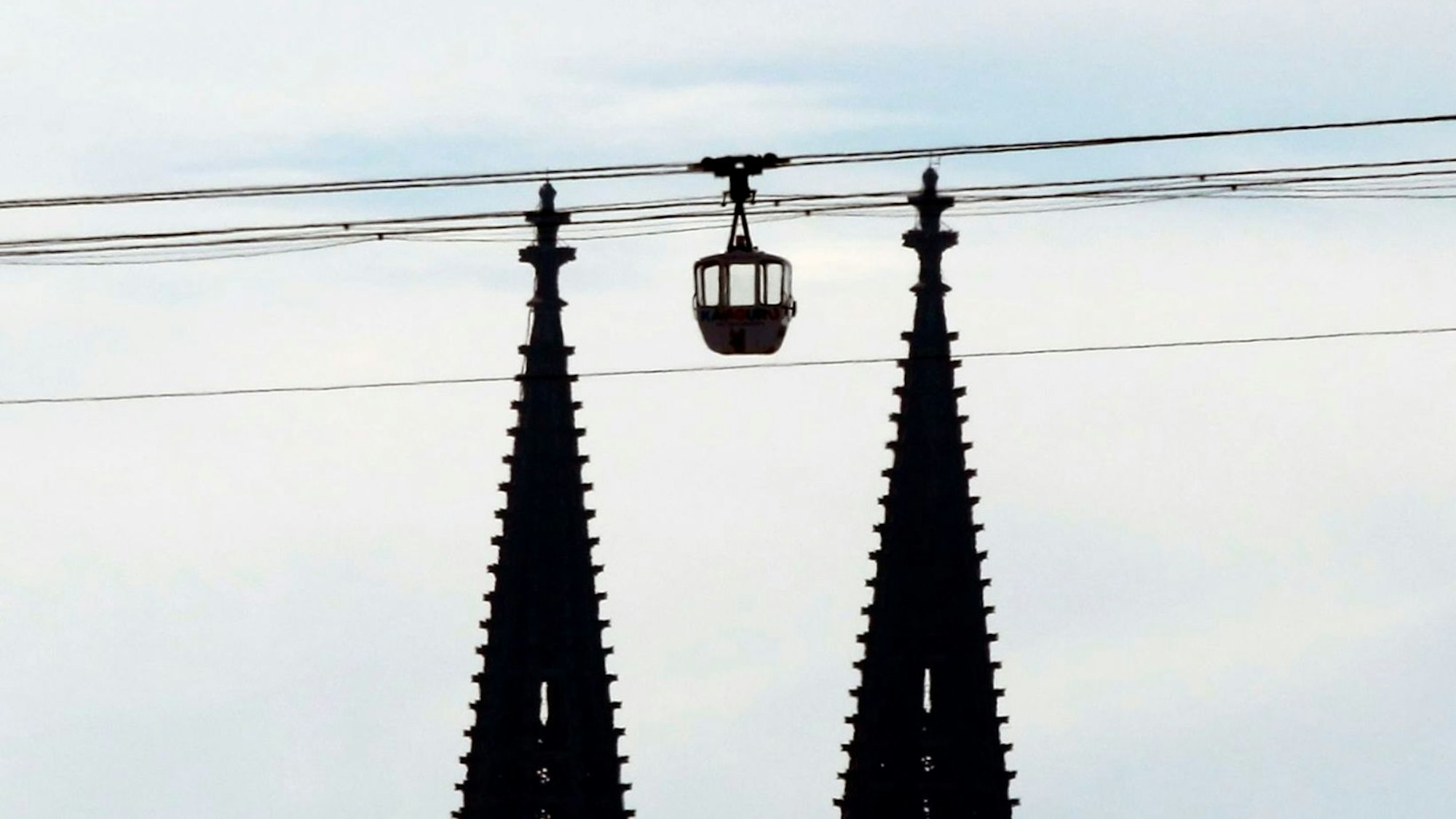 Die Seilbahn fährt wieder. Eine Gondel schwebt zwischen den beiden Türmen des Kölner Doms. (Archivbild)