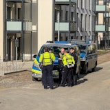 Gevelsberg: Polizisten stehen vor einem Polizeiauto. Nach einer mutmaßlichen Entführung in Gevelsberg bei Hagen suchen die Beamten nach einem Auto.