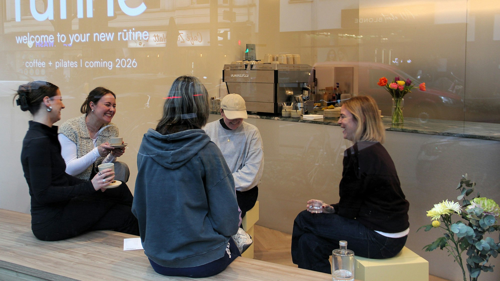 Fünf Frauen sitzen hinter einer Scheibe im Ladenlokal eines Cafés.