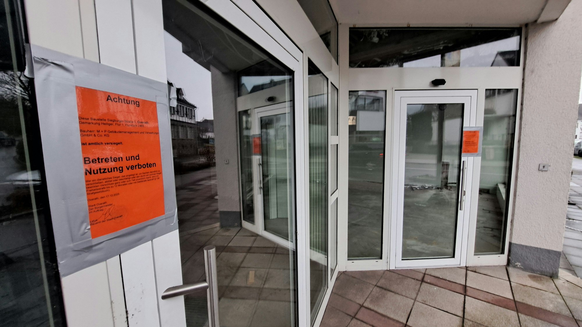 Zu sehen ist ein Geschäft, das mit einem orangefarbenen Aufkleber als gesperrt markiert ist.