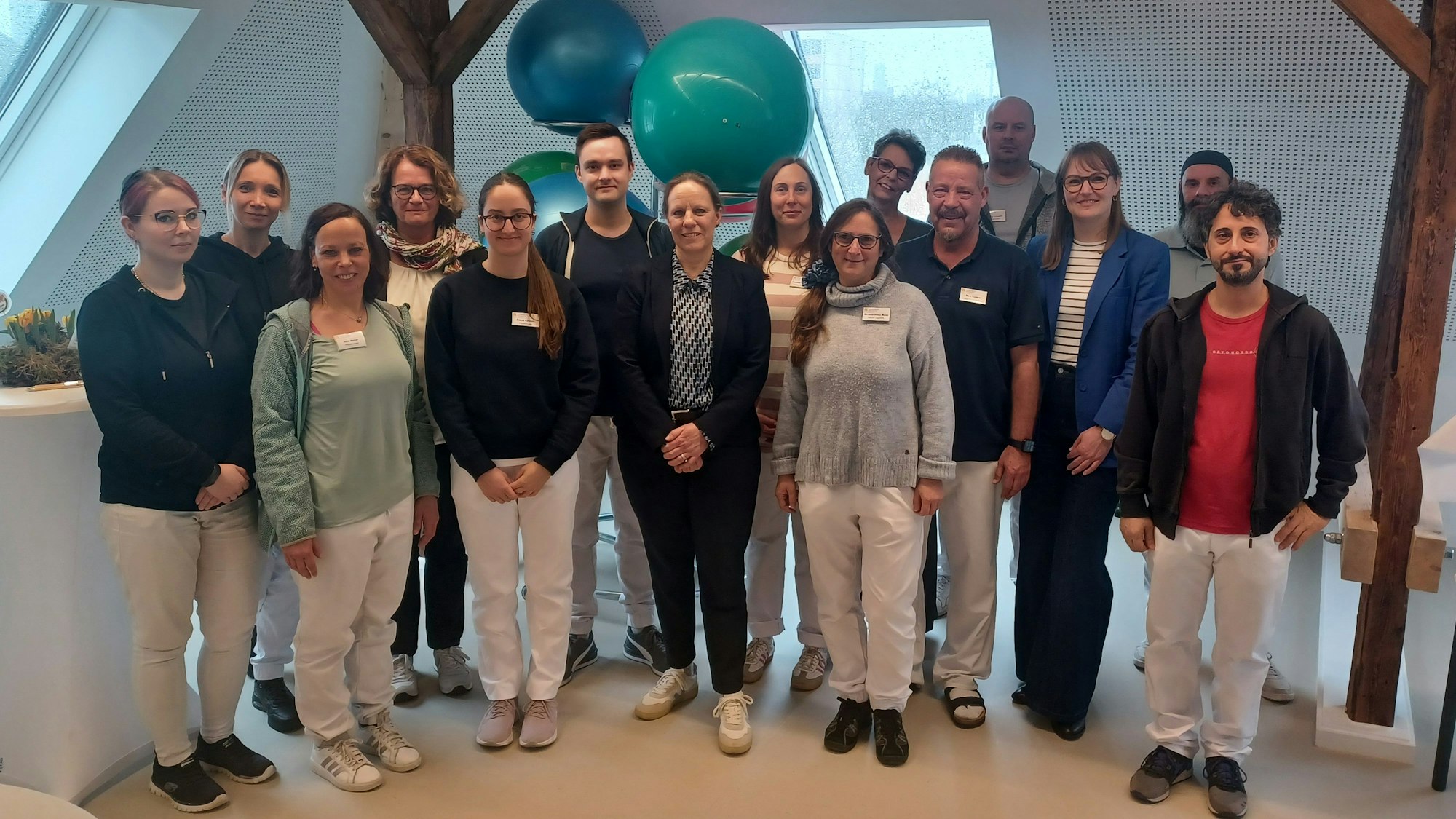 Eine Gruppe steht in einem Raum, in dem Physiotherapie stattfinden soll.