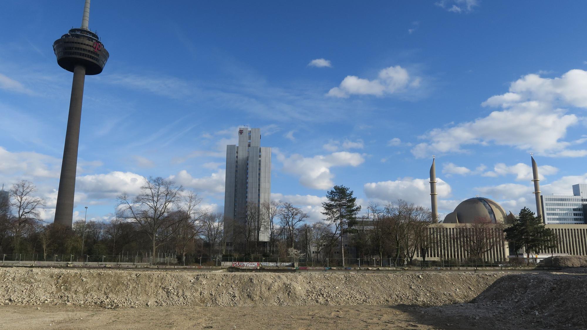 Hinter einem freigeräumten Baugrundstück sind der Colonius, ein Telekom-Hochhaus und die Moschee an der Venloer Straße zu sehen.