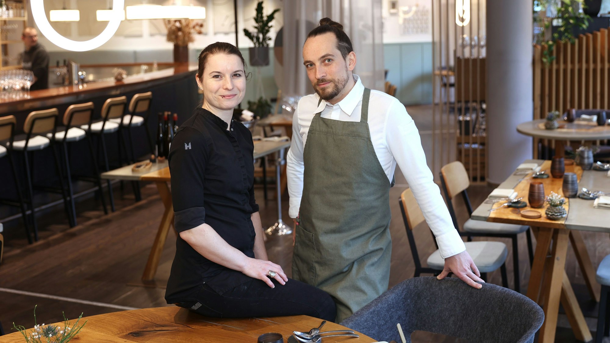Sonja Baumann und Erik Scheffler sind im Restaurant zu sehen. Sie lächeln in die Kamera.