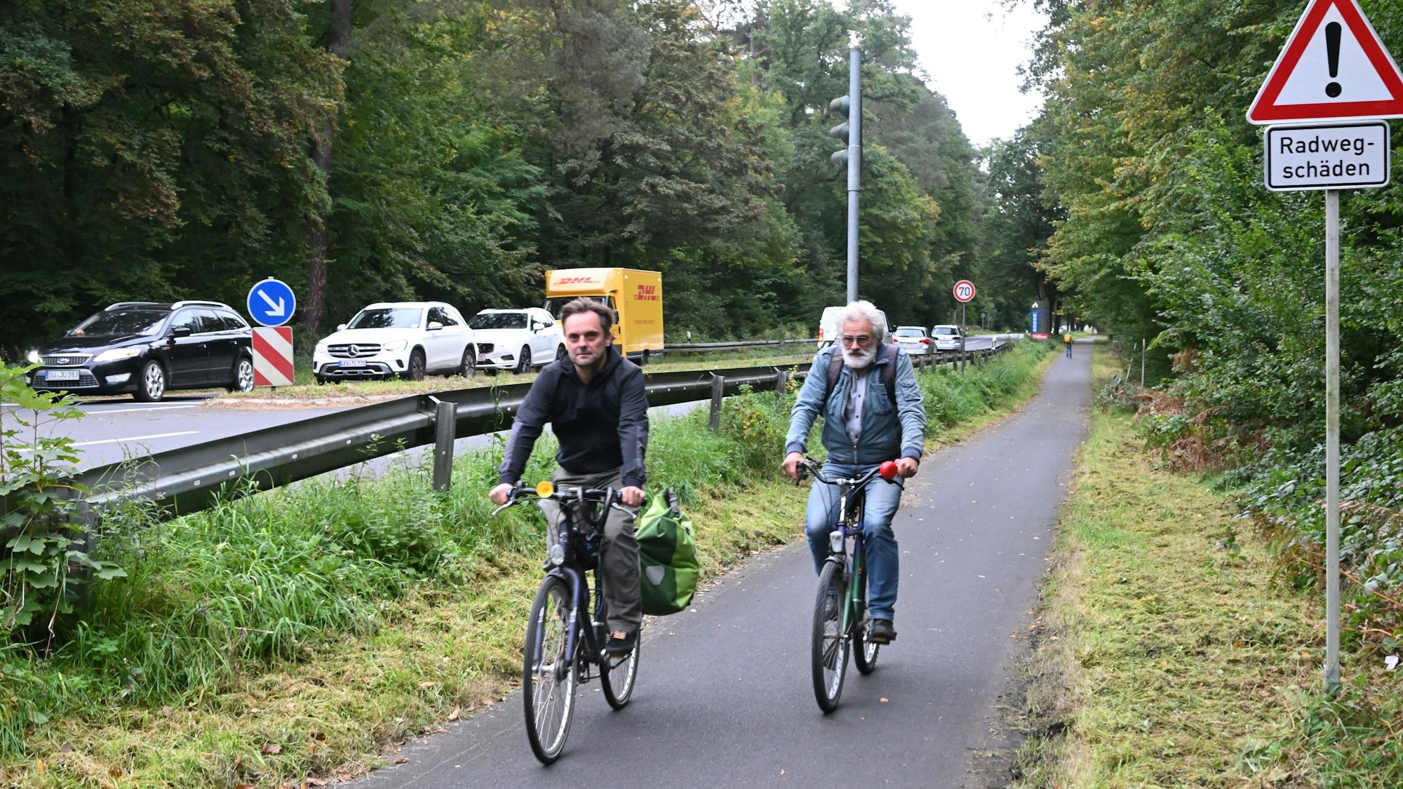 Zwei Radfahrer auf einem Radweg hinter einer Leitplanke