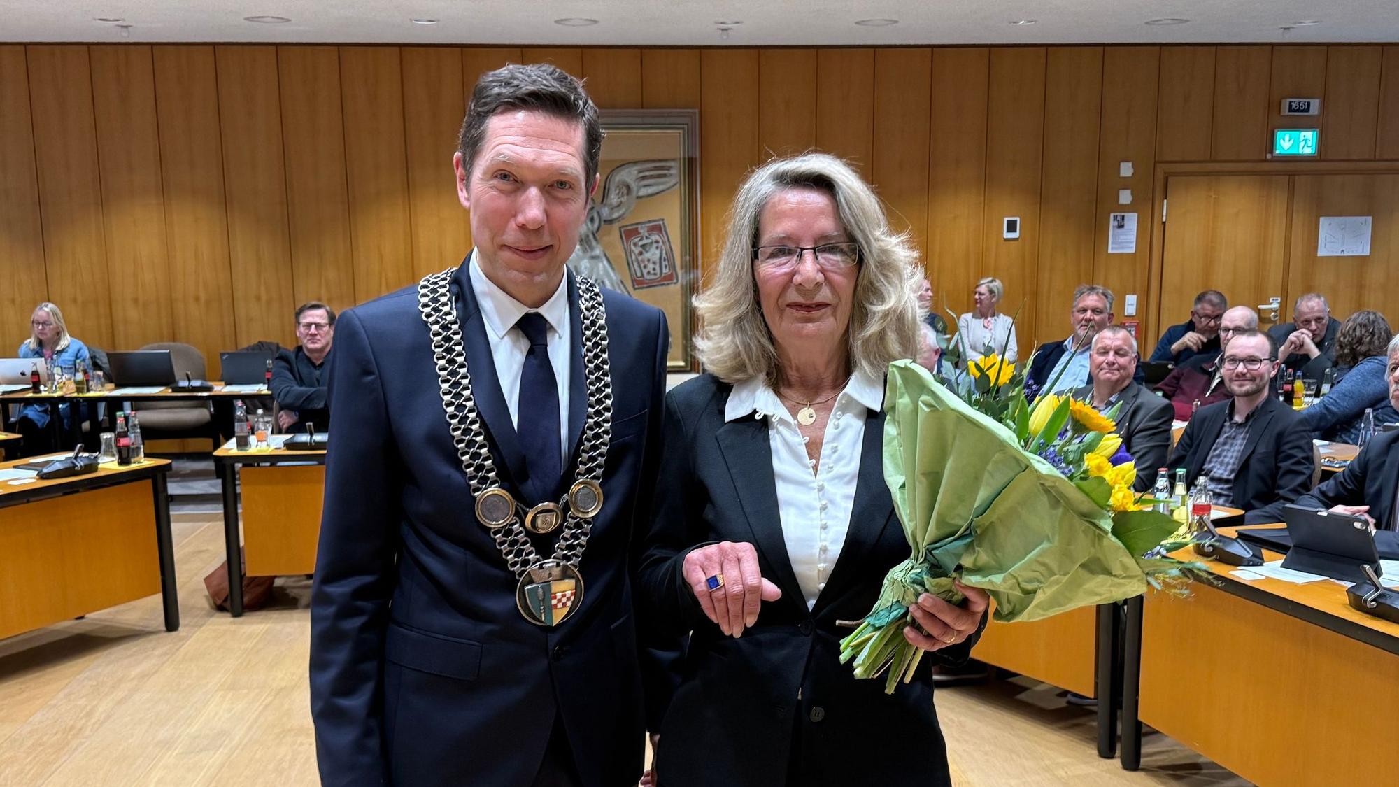 Bürgermeister Raoul Halding-Hoppenheit und Helga Auerswald mit einem Blumenstrauß und dem Ehrenring