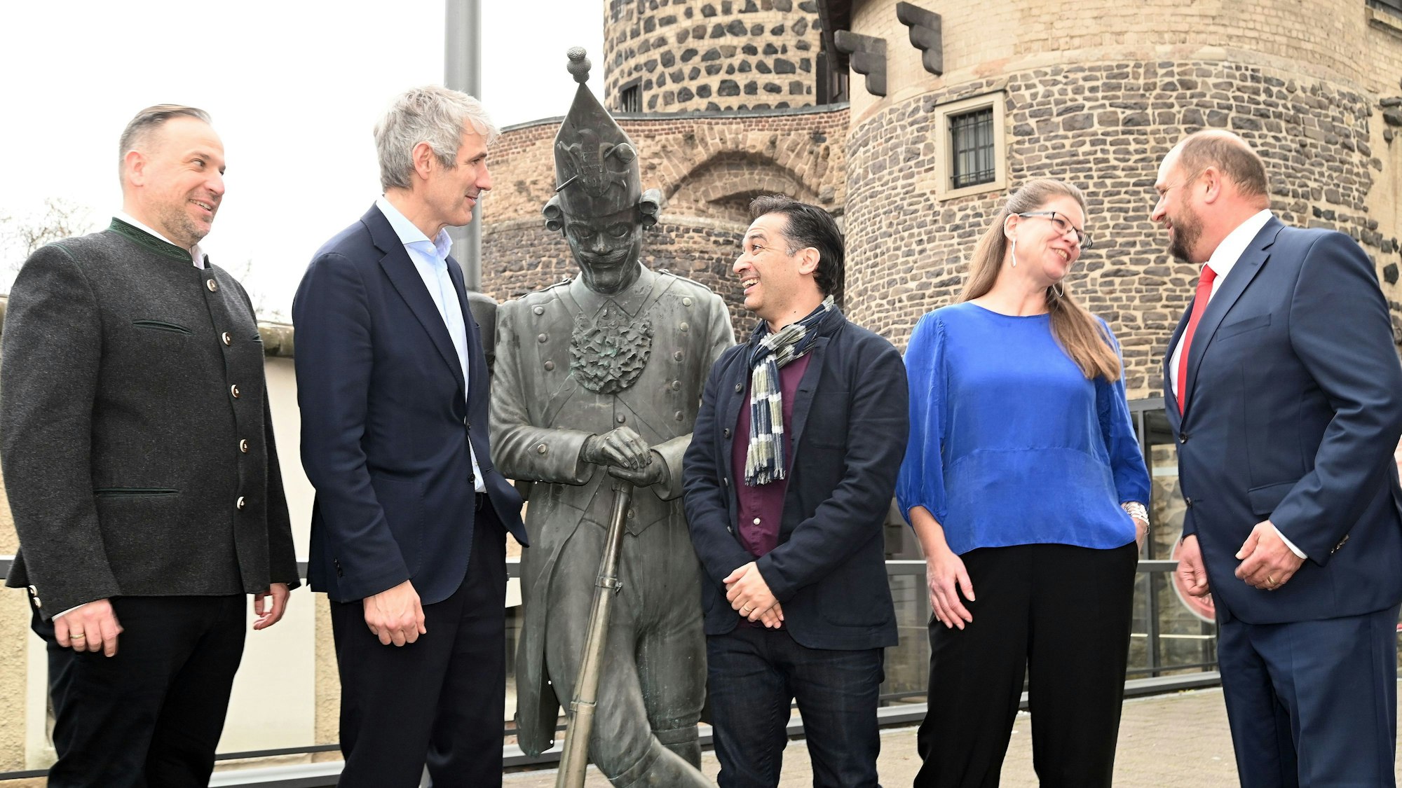 Fünf Menschen rahmen die Statue eines Karnevalisten ein.