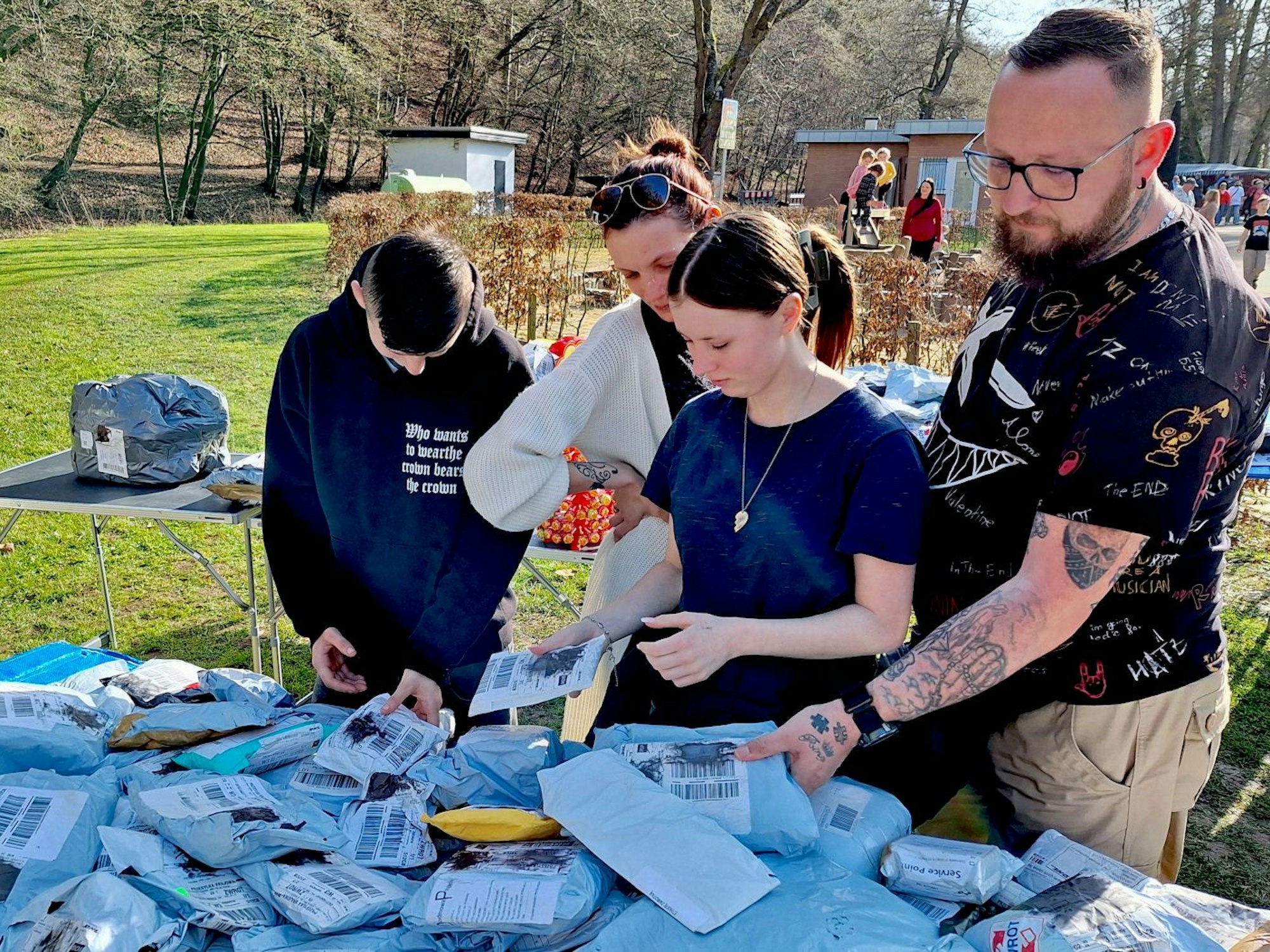 Auf einm Tisch liegen haufenweise Päckchen, eine Familie stöbert.