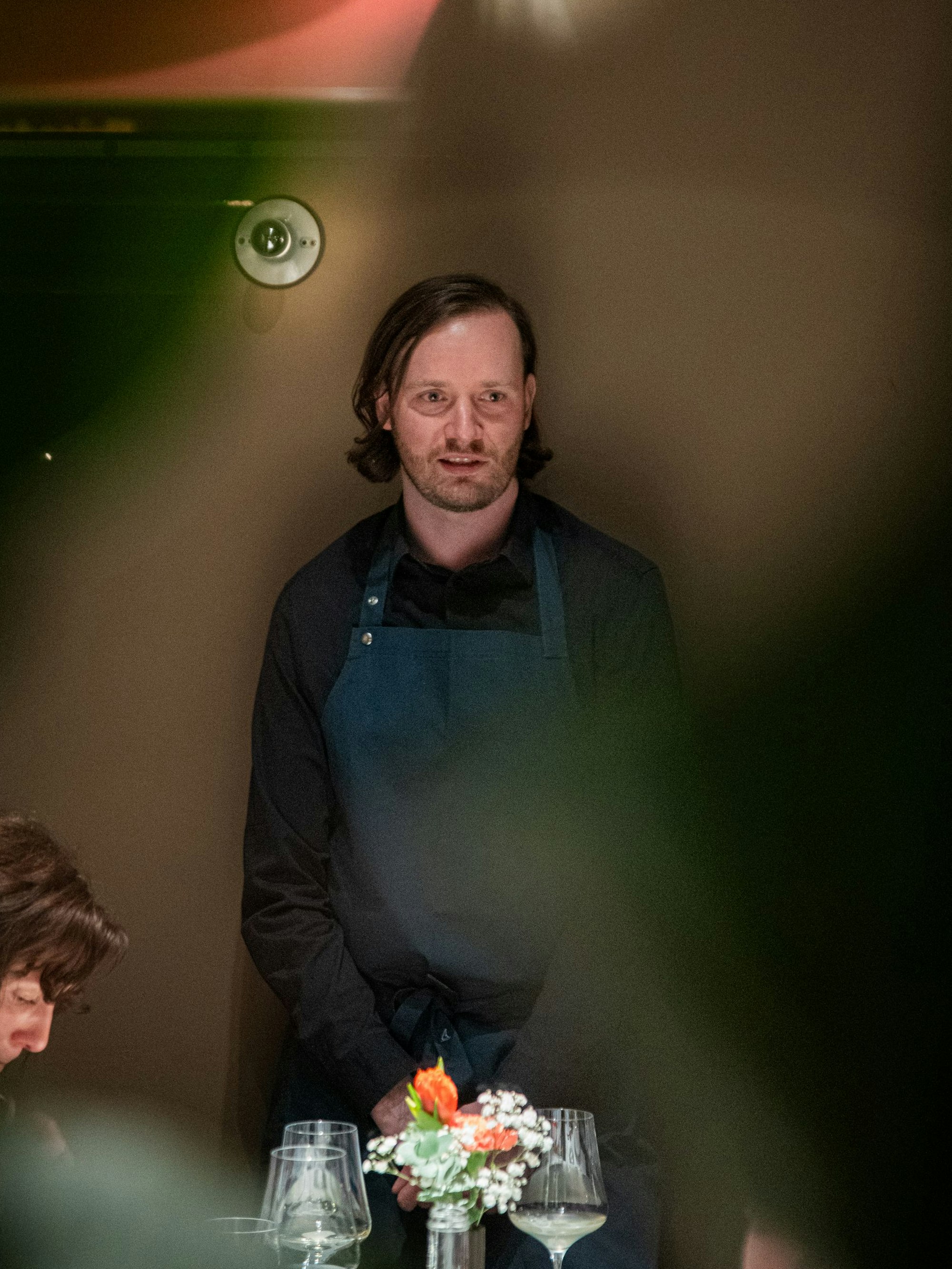 Winkelmann steht an einem eingedeckten Tisch und hat sich an die Gäste gewandt.