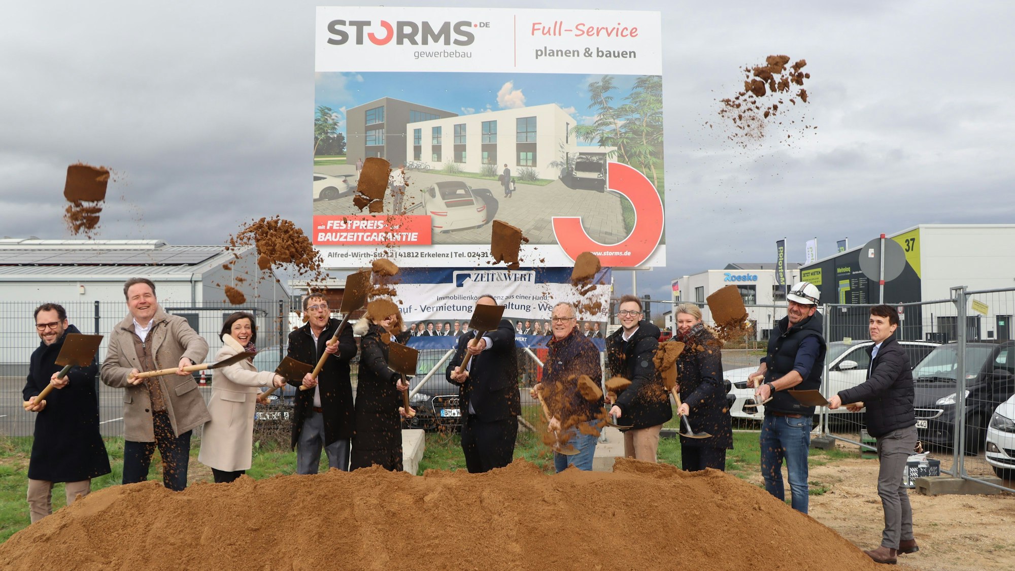 Elf Personen mit Spaten beim ersten Spatenstich. Vor ihnen ein Sandhaufen.
