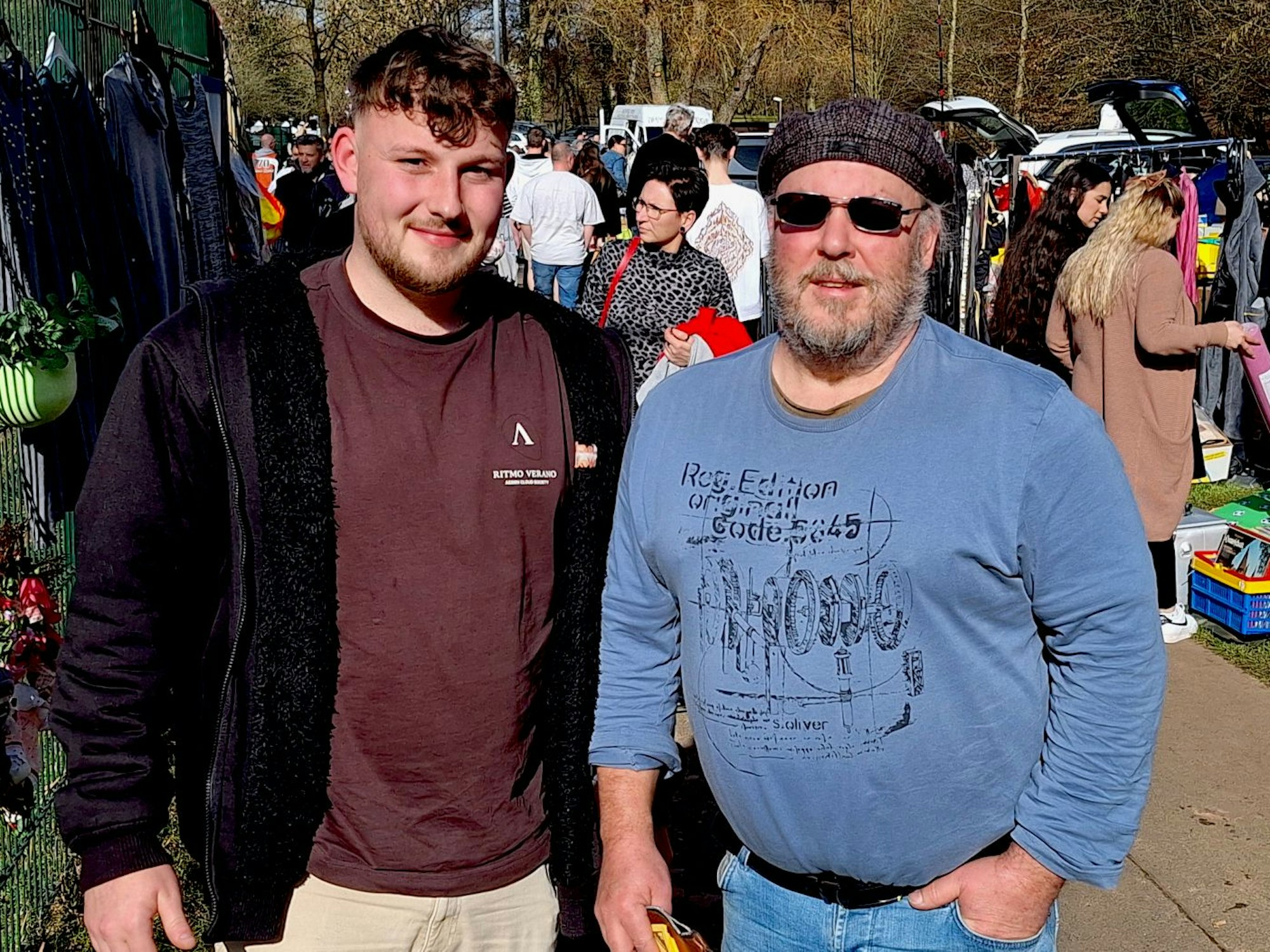 Zwei Männer stehen nebeneinander auf einem Flohmarkt.