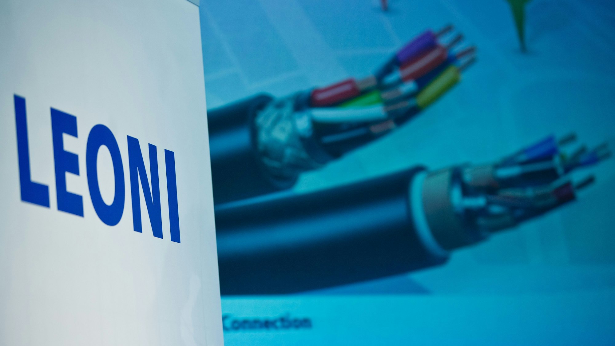 Logo des Kabel-Herstellers Leoni AG. Im Hintergrund Kabelbünde des Unternehmens