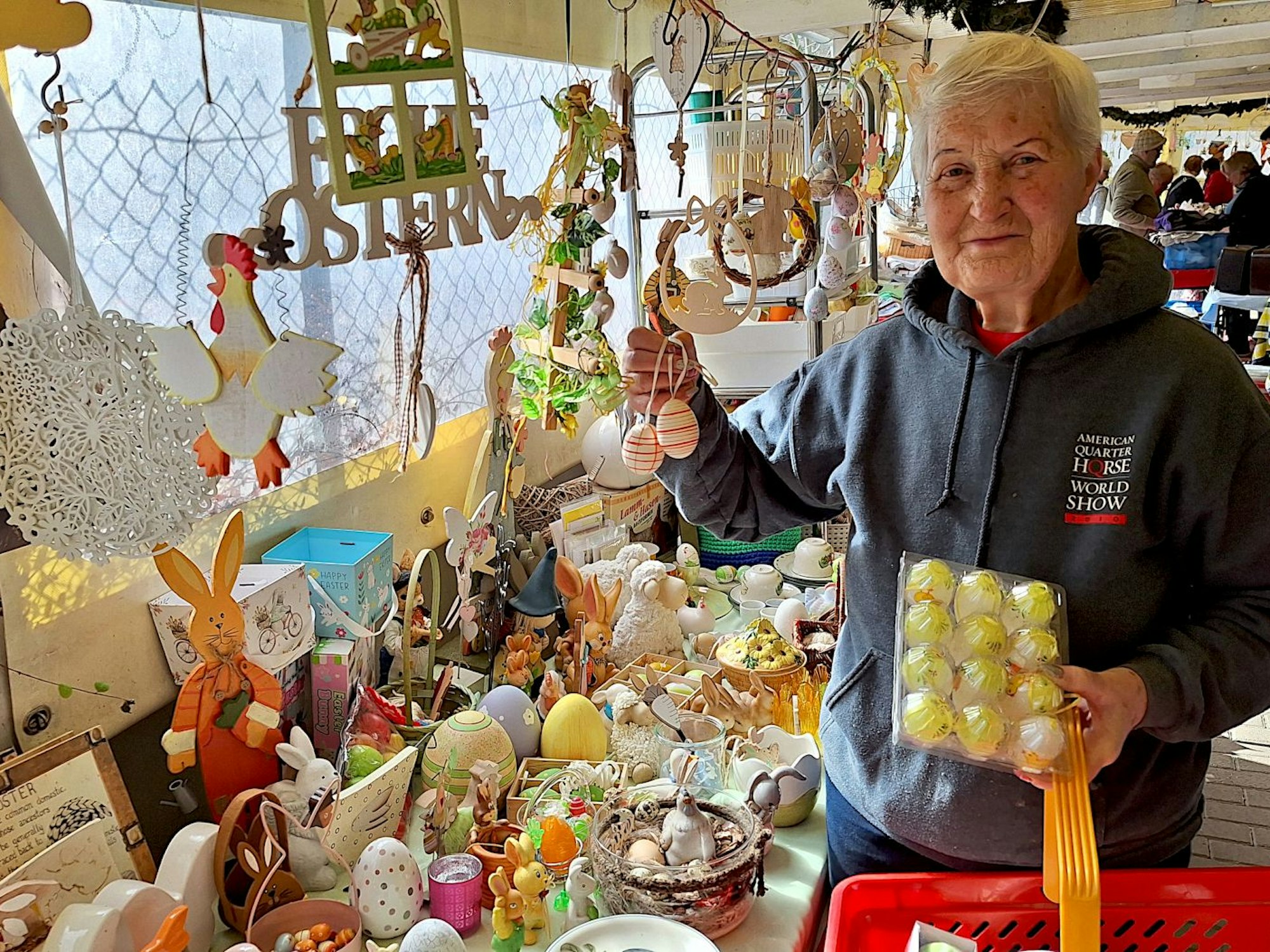 Eine Frau steht an einem Stand, an dem Oster-Dekoration verkauft wird.