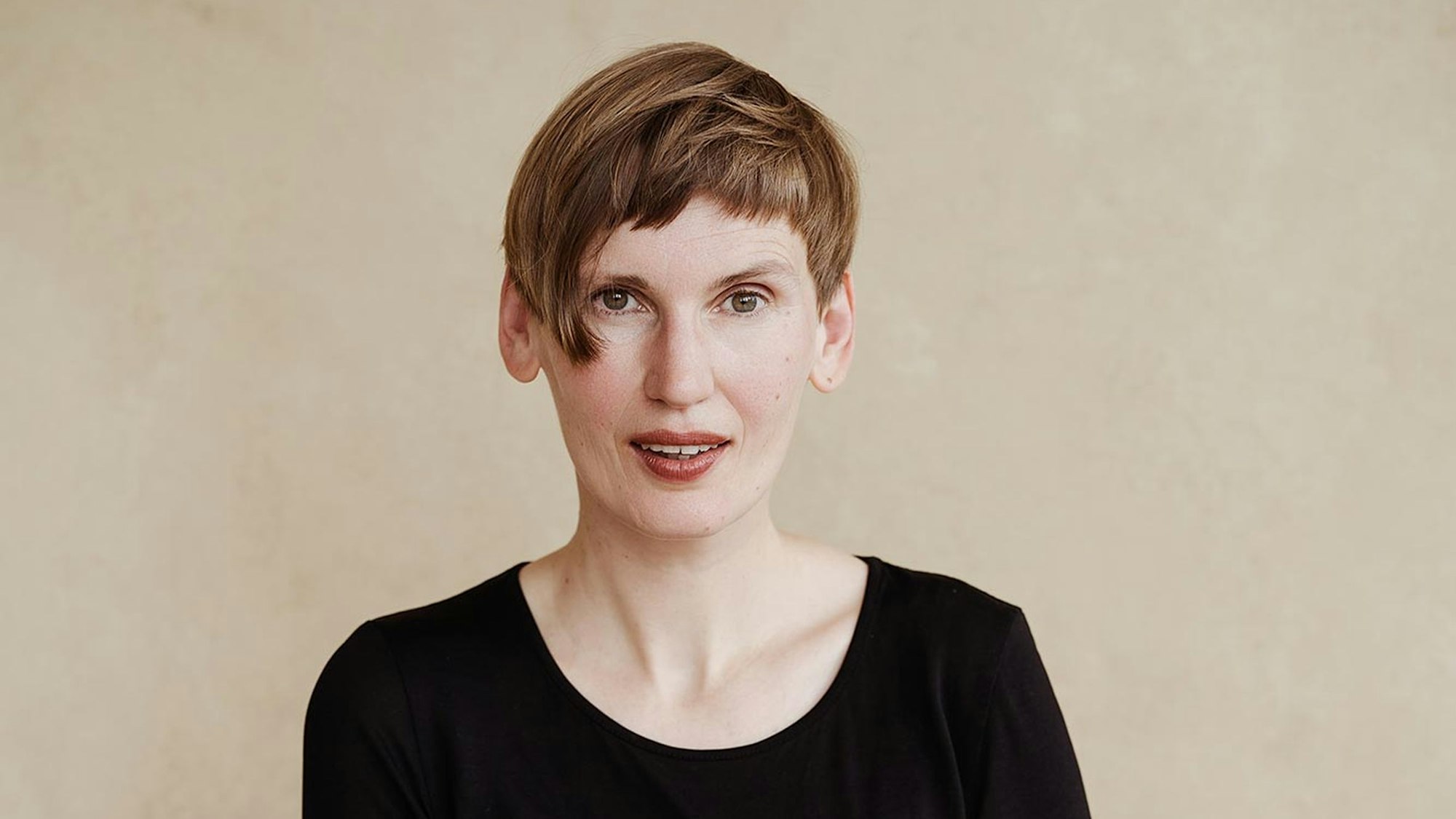 Eine Frau blickt zaghaft lächelnd in die Kamera.