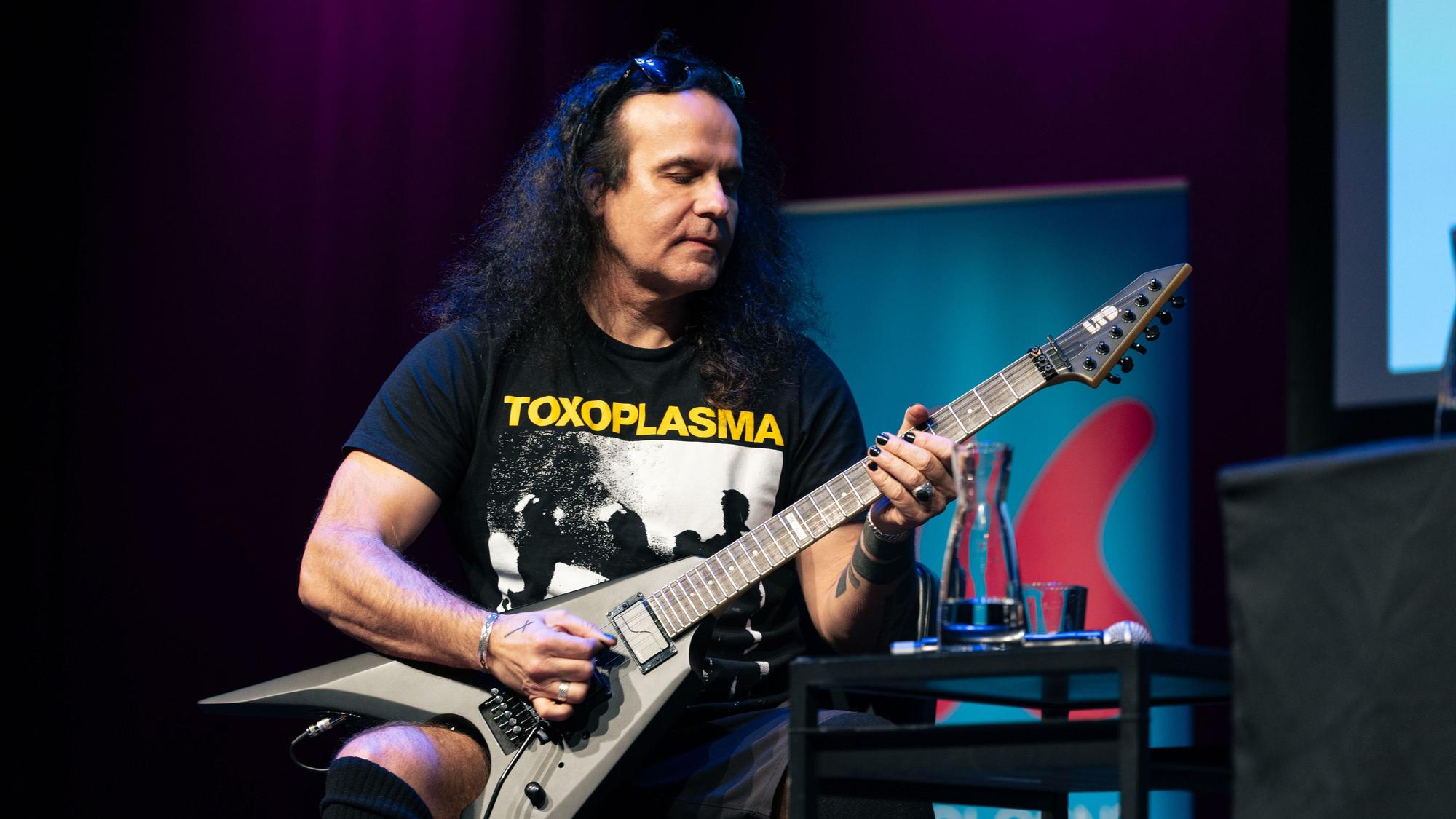 Ein Mann mit langen schwarzen Haaren spielt Gitarre.