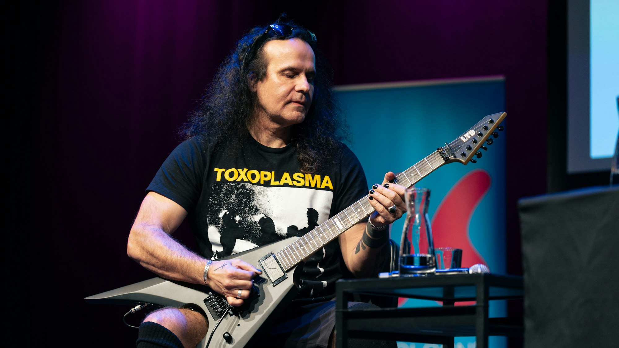 Ein Mann mit langen schwarzen Haaren spielt Gitarre.