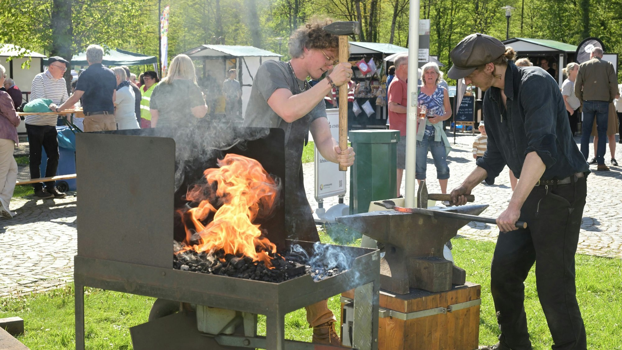 Schmiede schlagen auf ein Stück Eisen, das auf einem Amboss liegt.