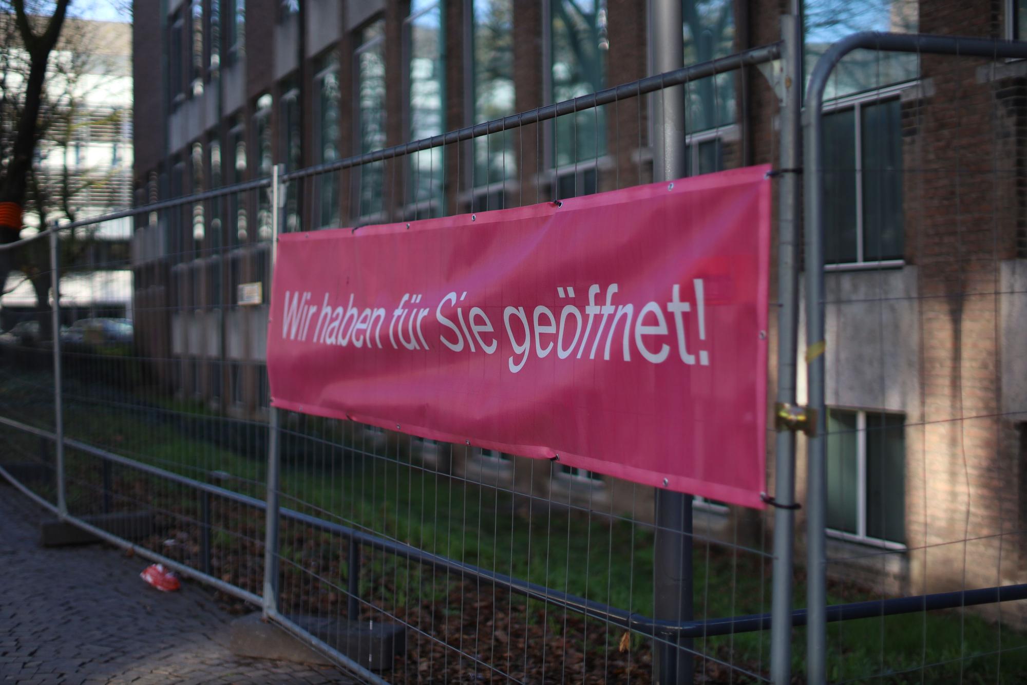 Auf einem Transparent steht: „Wir haben für Sie geöffnet.“