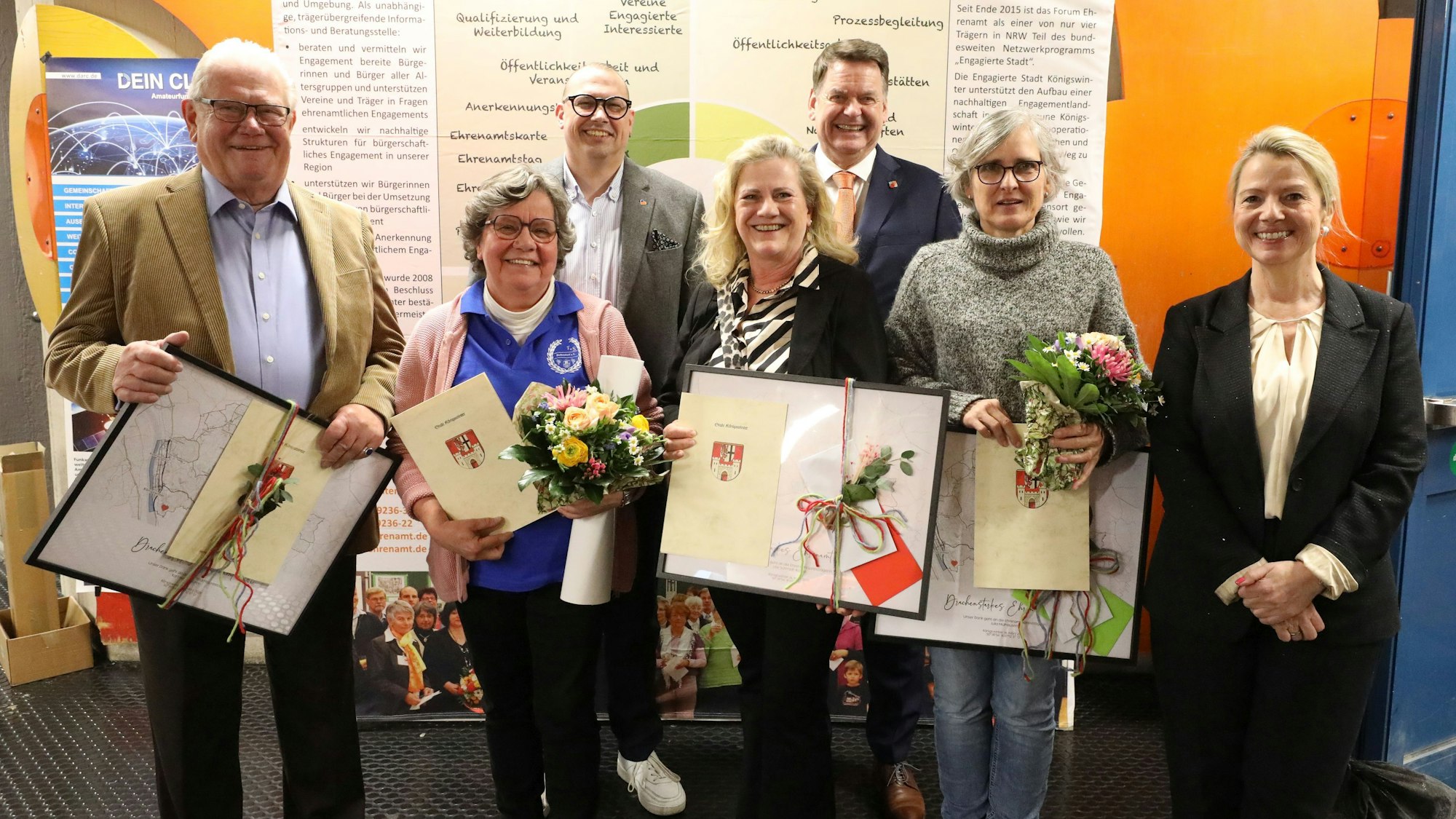 Eine Gruppe von Menschen, zum Teil halten sie Bilderrahmen und Urkunden in den Händen.