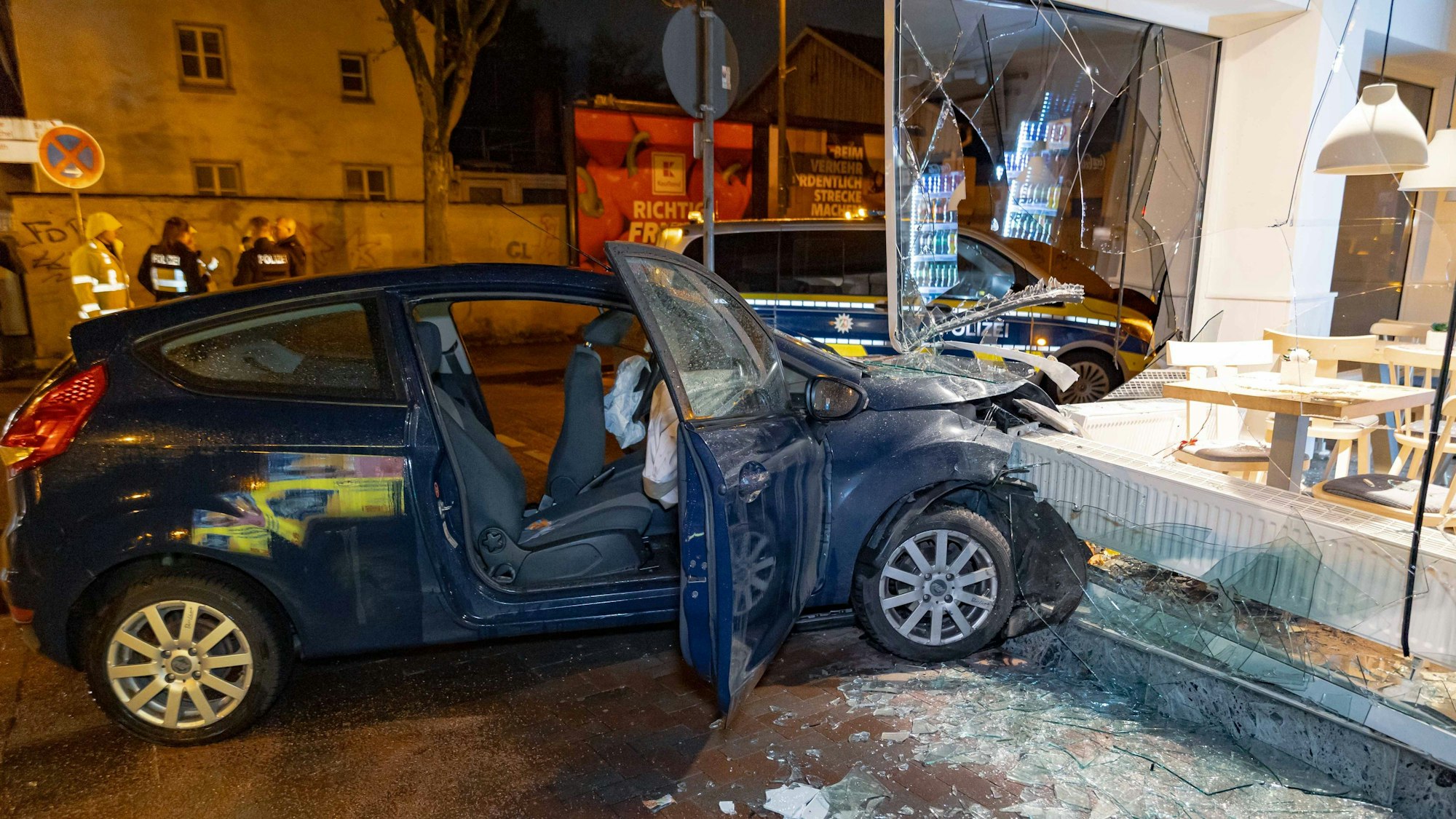 13.03.2026, Nordrhein-Westfalen, Leverkusen: Ein Autowrack steht im zertrümmerten Schaufenster einer Bäckerei.