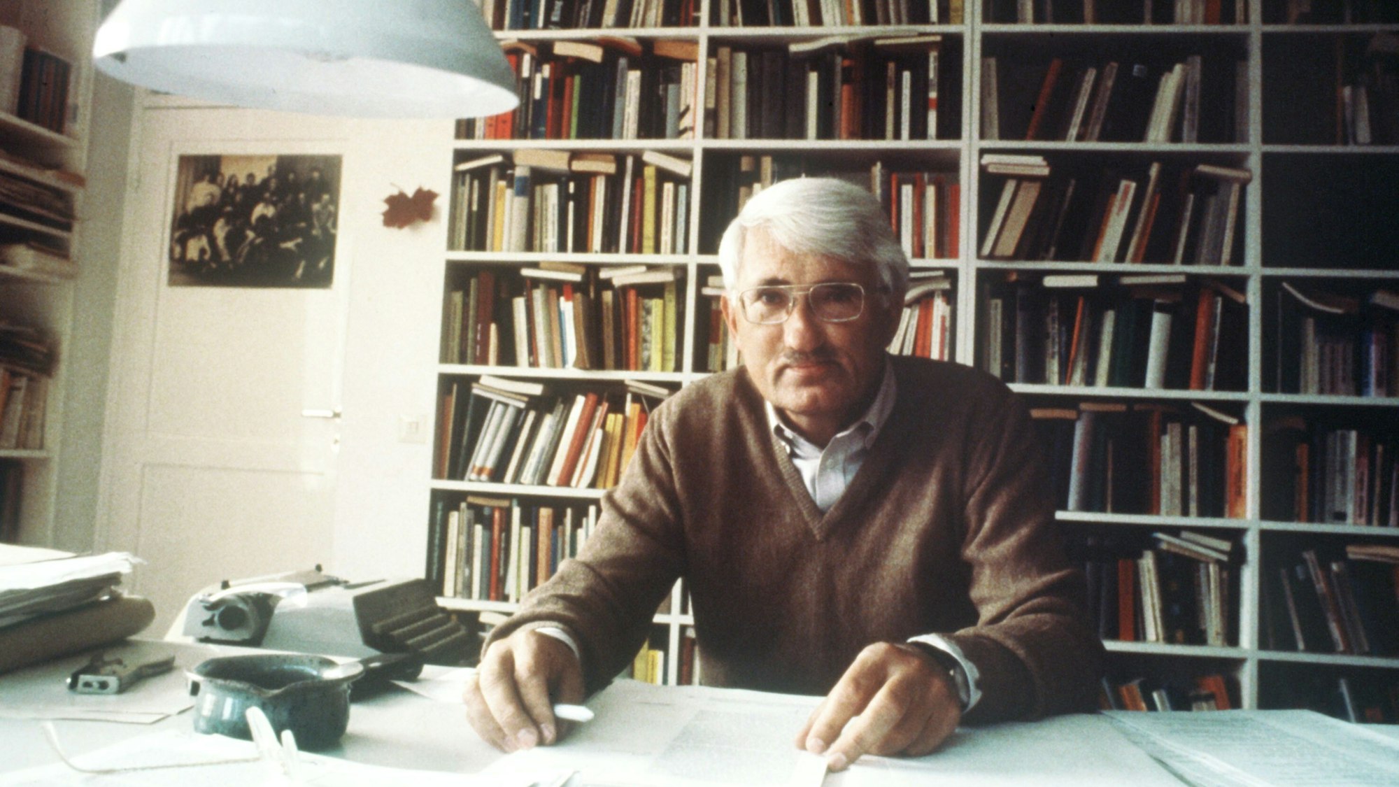 Jürgen Habermas, sitzt vor einer Bücherwand an seinem Schreibtisch.