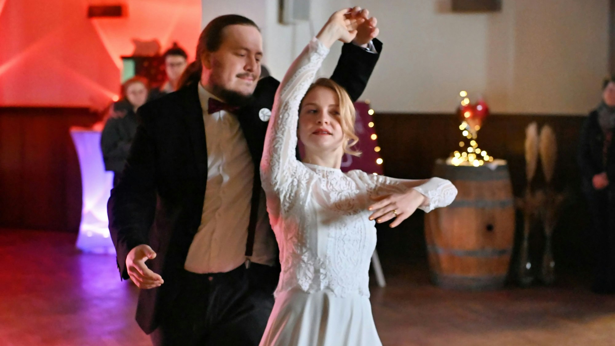 Eine Frau im Brautkleid und ein Mann im schwarzen Anzug tanzen zusammen.