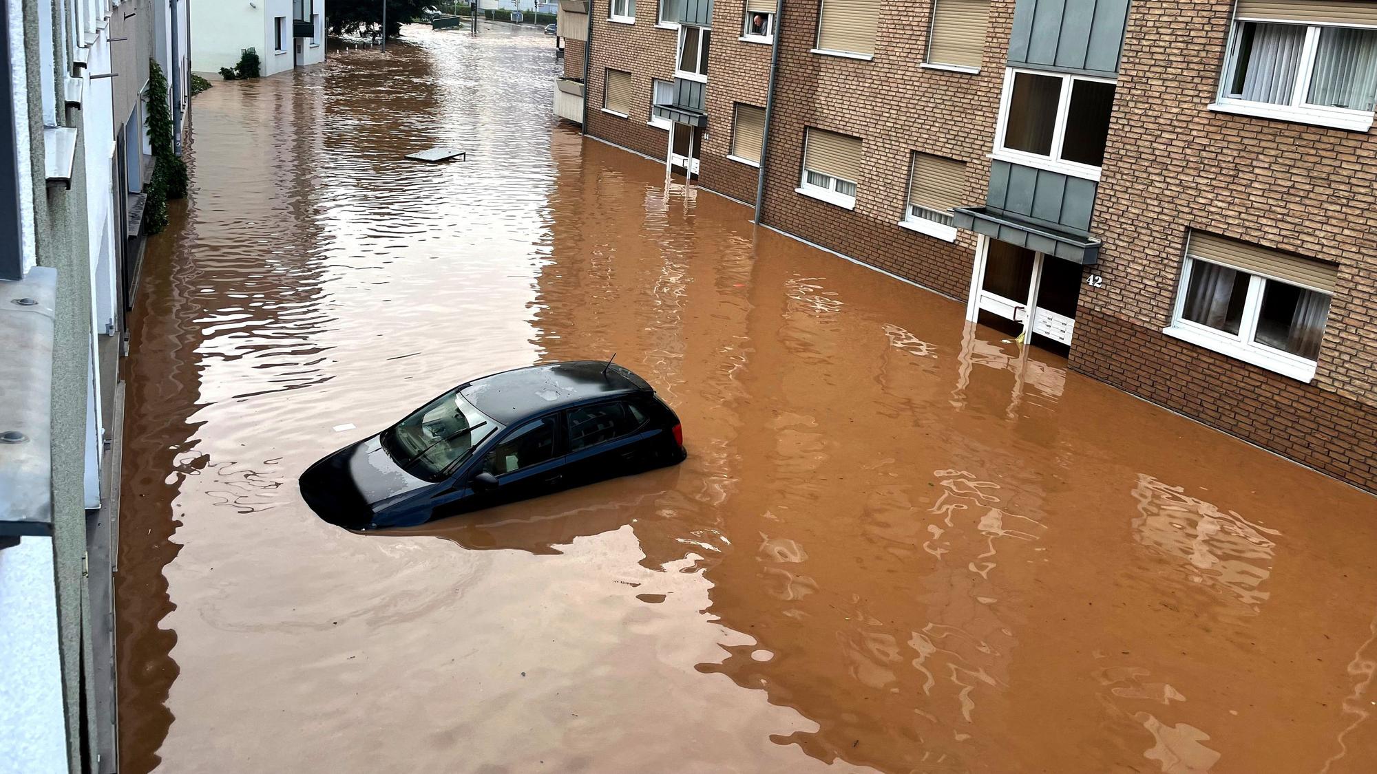 Das Bild zeigt ein Auto im Wasser. An der Fassade ist zu erkennen, dass der Wasserstand in der Nacht deutlich höher war.