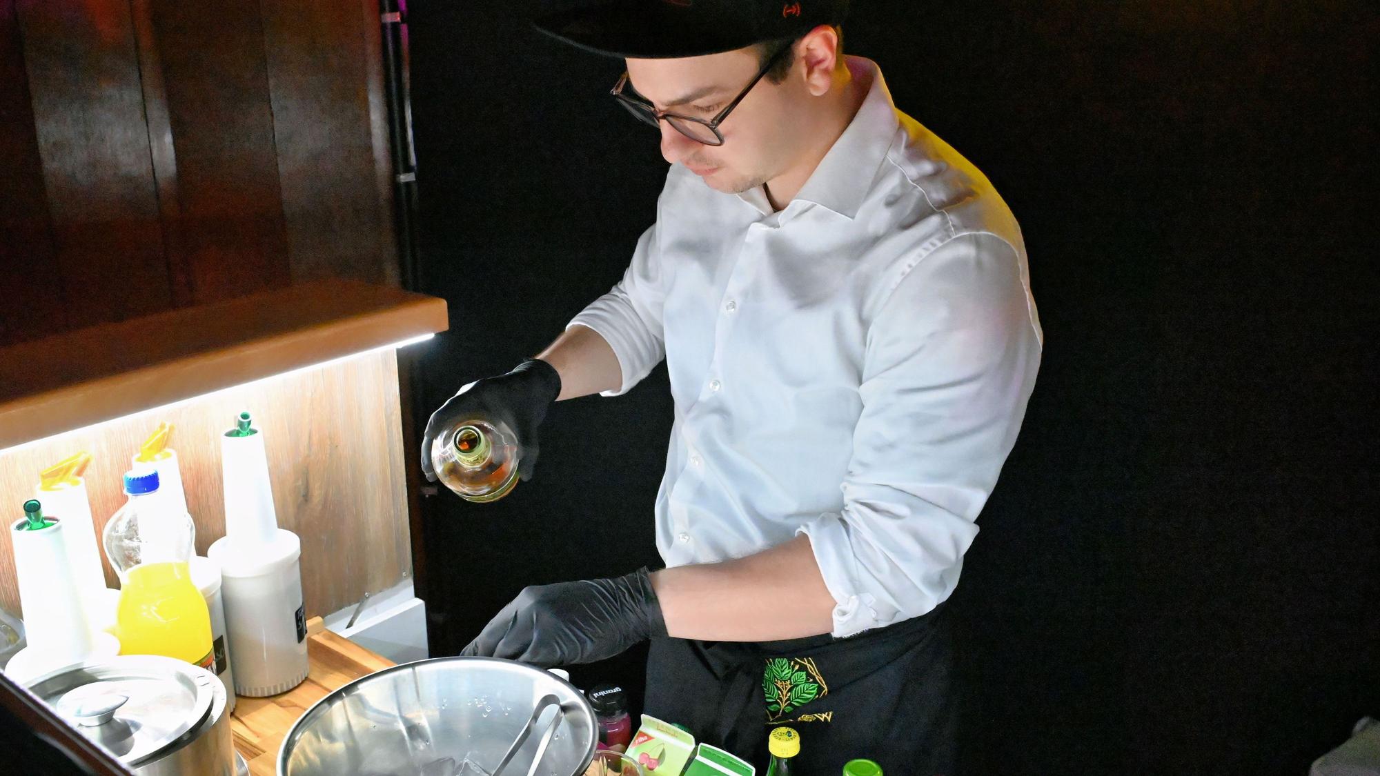 Alexander Bigelmaier mixt hinter einem Tresen einen Cocktail.