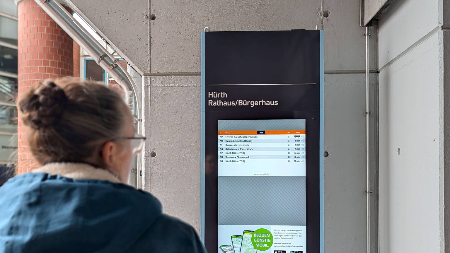 Das Foto zeigt eine Passantin vor der elektronischen Fahrplan-Stele am Rathaus.