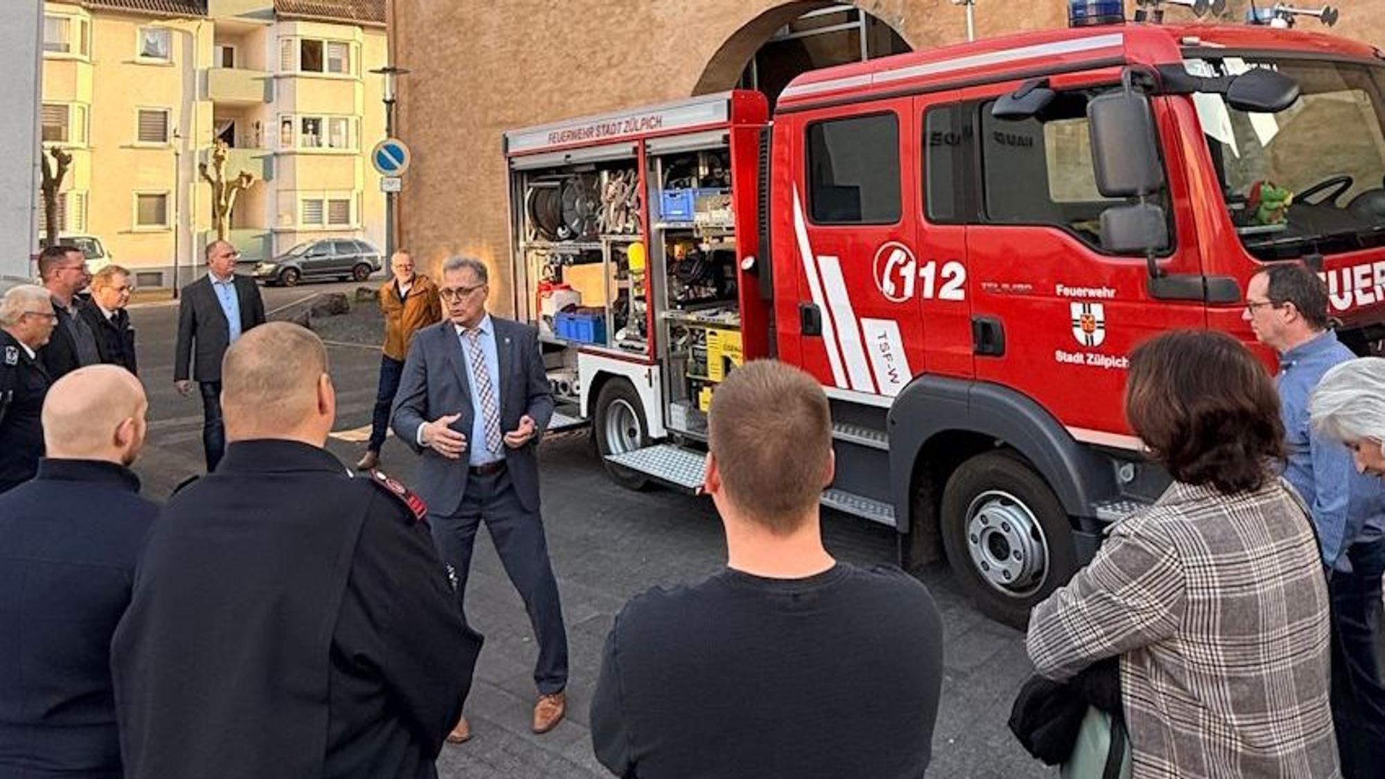 Menschen stehen um ein Feuerwehrauto herum.
