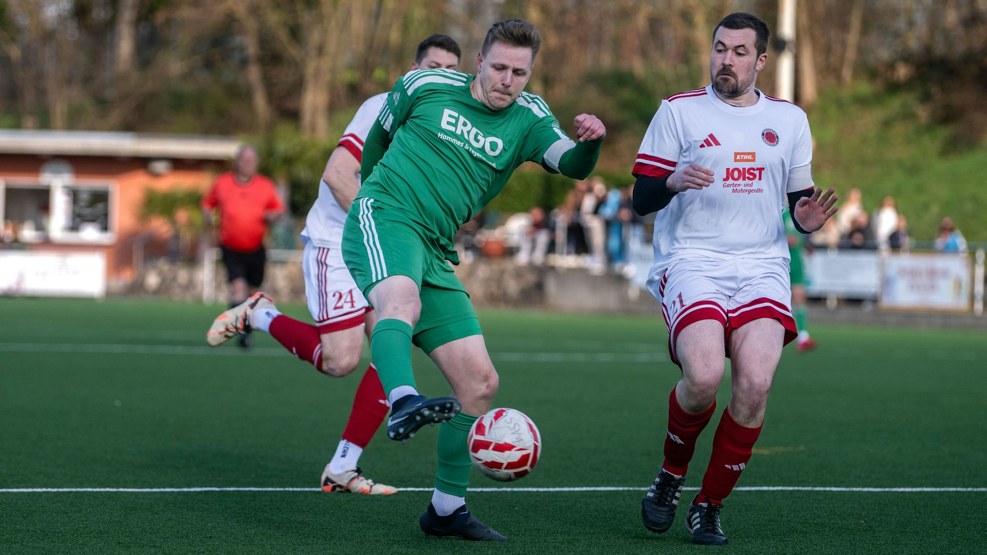 Das Bild zeigt Jens Knebel, der den Ball schießt. Lommersums Abwehrspieler kommt zu spät.