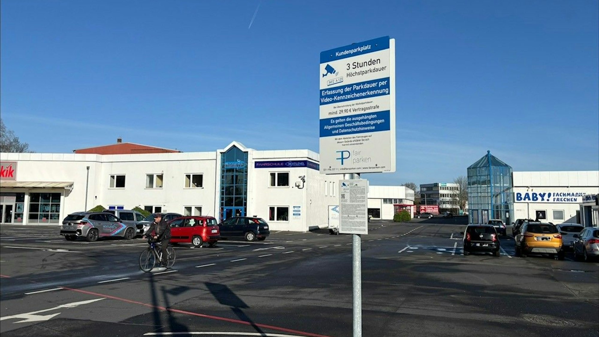 Auf dem Bild ist ein großer Parkplatz und ein Schild mit einem Hinweis auf Gebühren zu sehen.