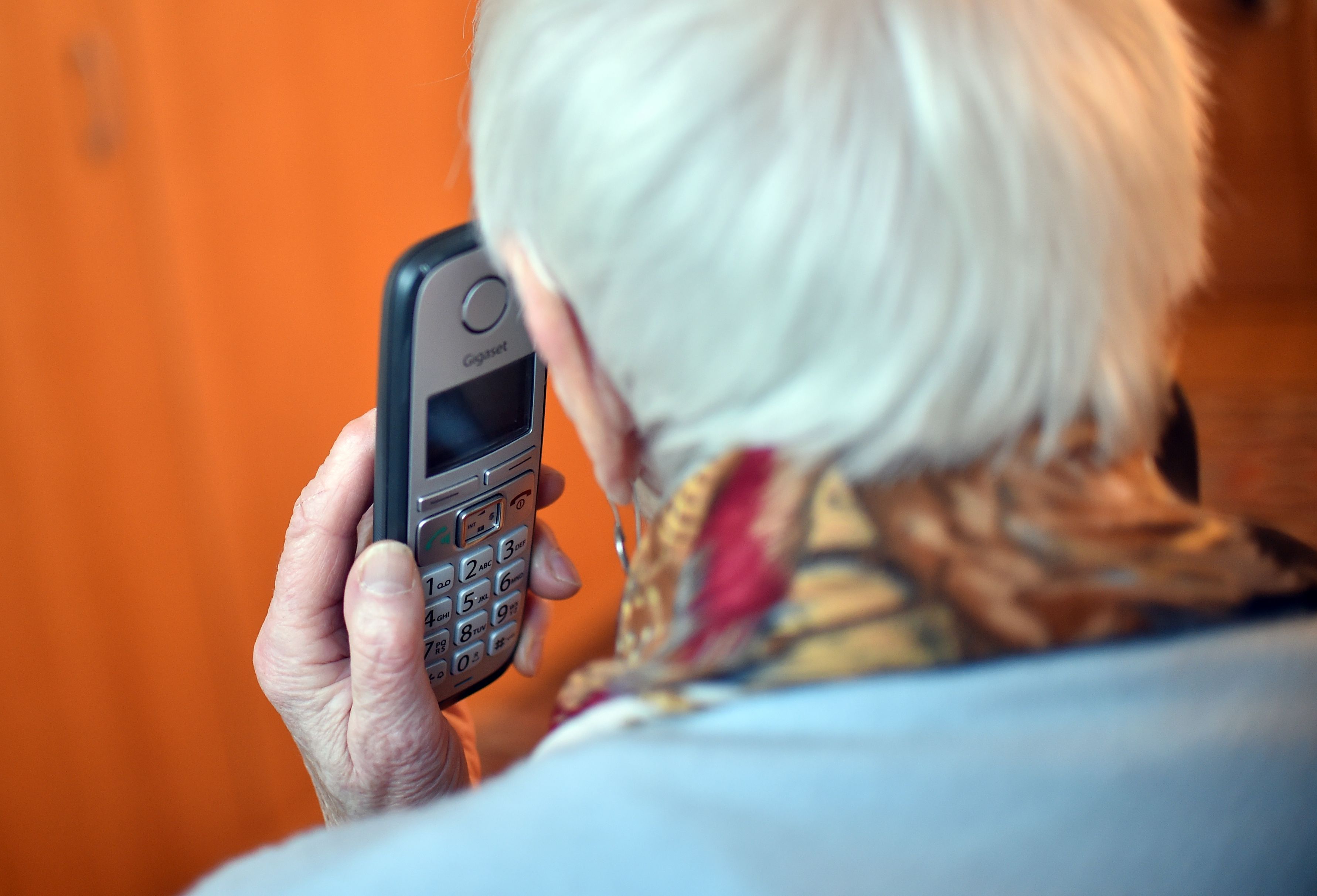 Eine Seniorin hält ein Handy an ihr Ohr (gestellte Szene).