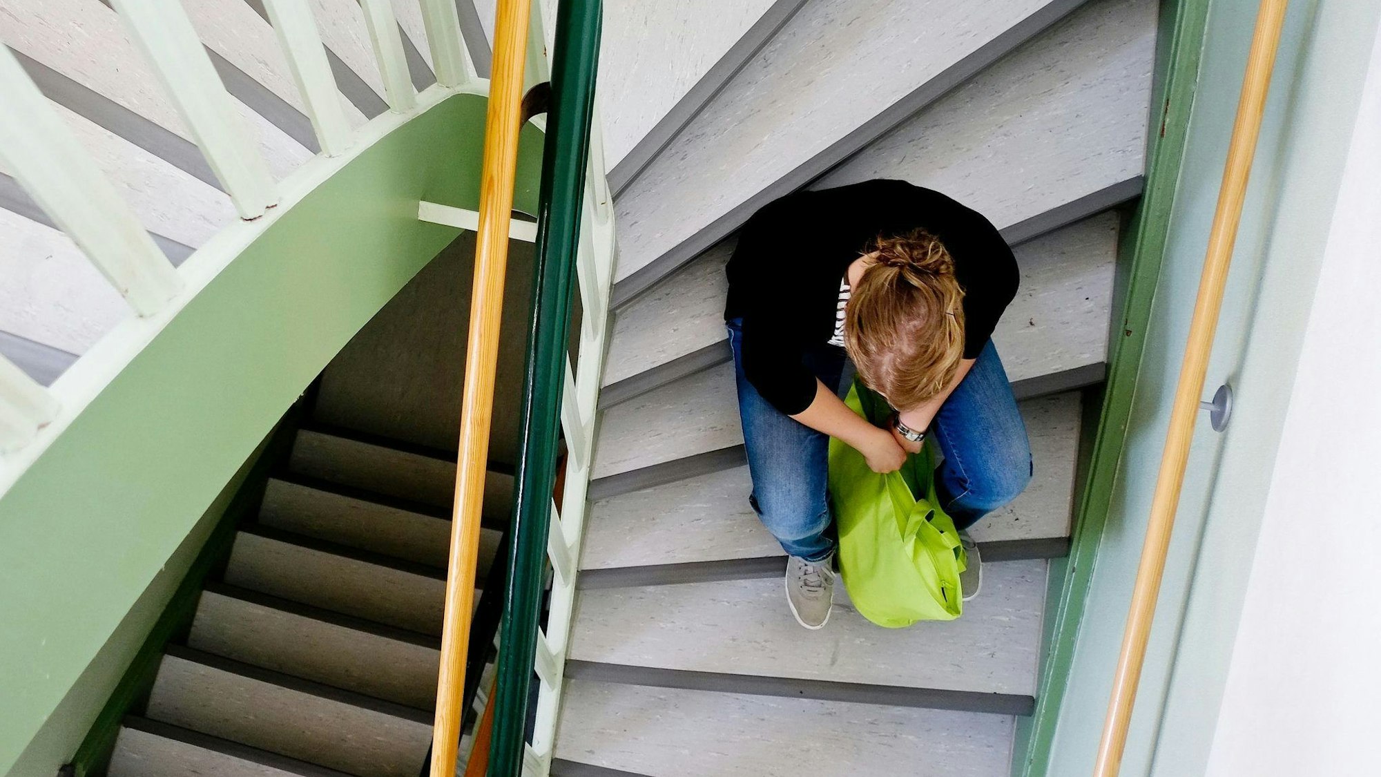 Eine Frau sitzt allein auf einer Treppe.