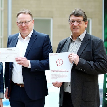 Stadtdirektorin und Wahlleiterin Andrea Blome, Kölns OB Torsten Burmester und Wahlamtsleiter Andreas Zinn (v. l.) stellen die Abstimmungsunterlagen zum Ratsbürgerentscheid Olympia vor.