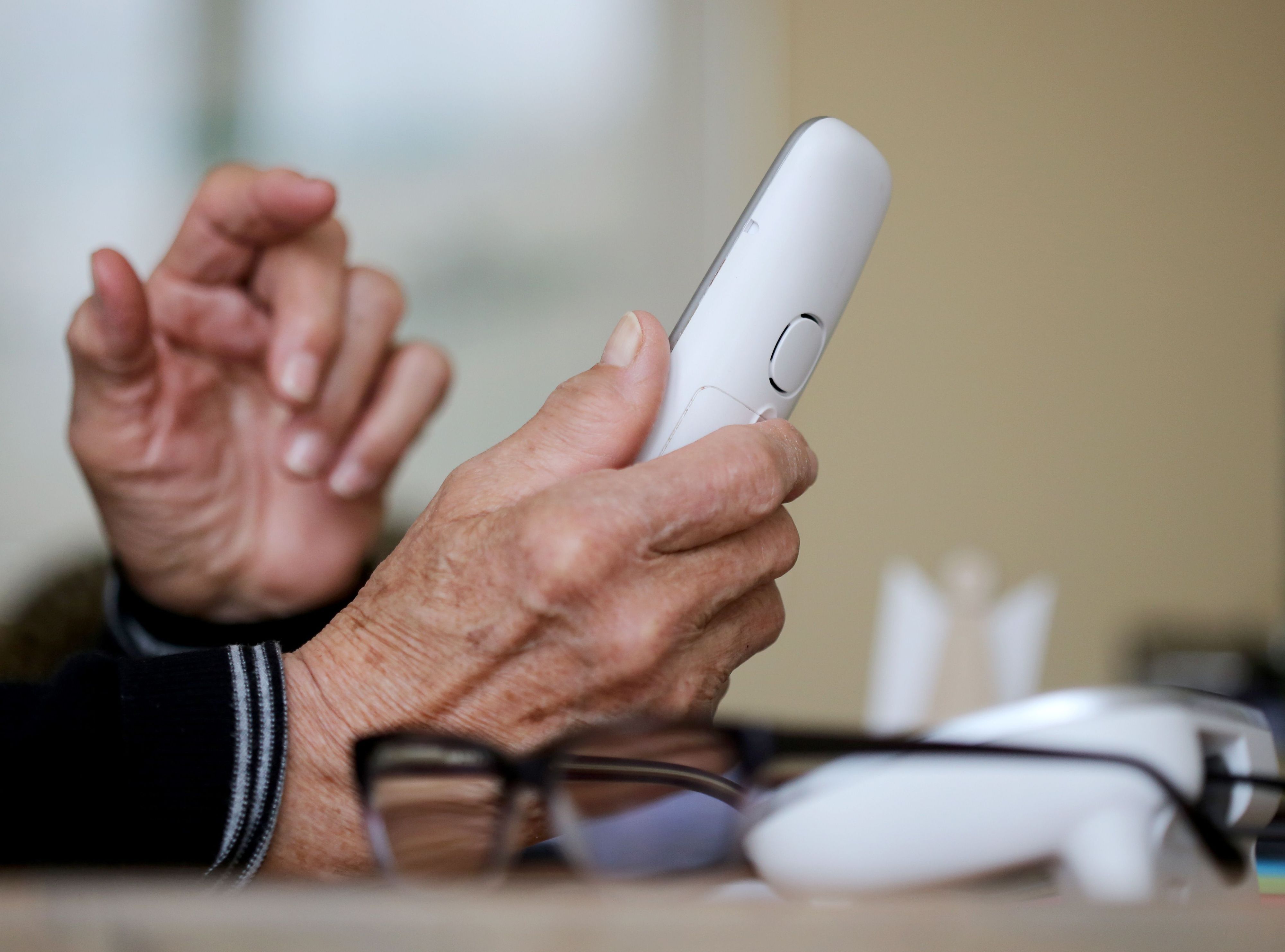 Eine ältere Dame nimmt in ihrer Wohnung ein Telefongespräch an.