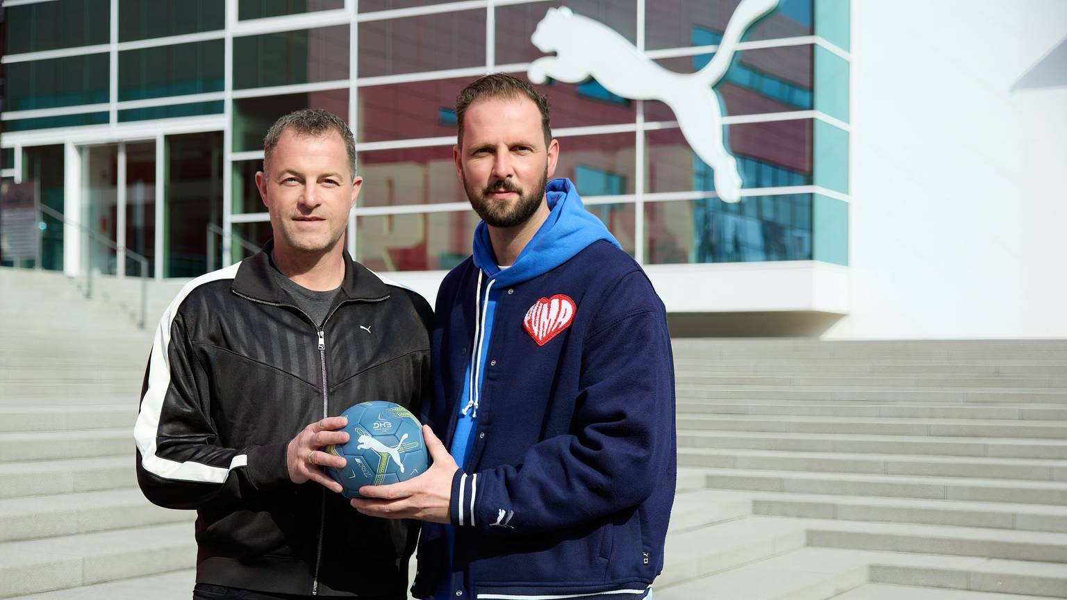Puma wird neuer Ausrüster des VfL Gummersbach: Arthur Hoeld und VfL-Geschäftsführer Christoph Schindler vor der Untrenehmenszentral mit einem Handball in der Hand.