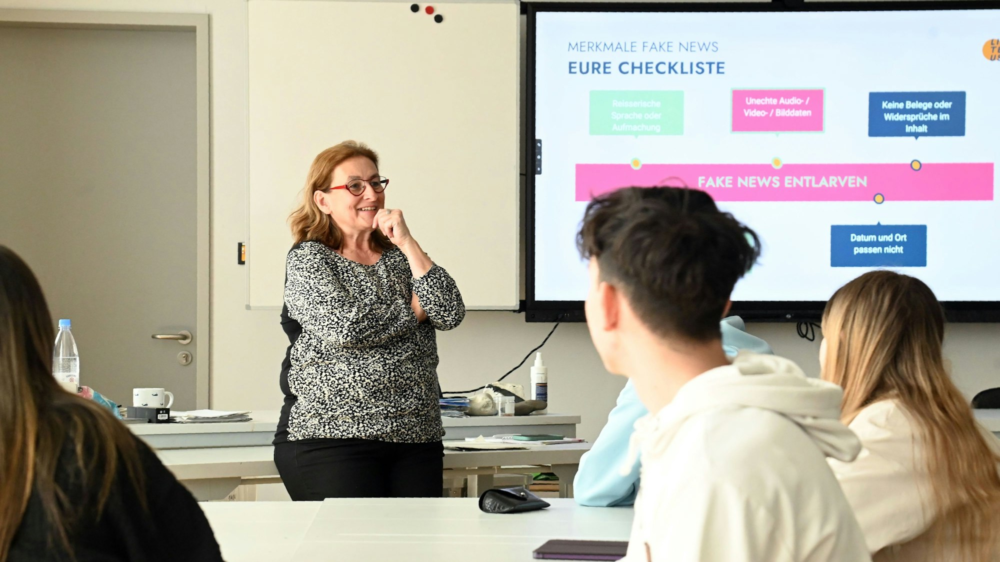 Eine Frau steht vor einer Jugendlichen in einem Klassenraum