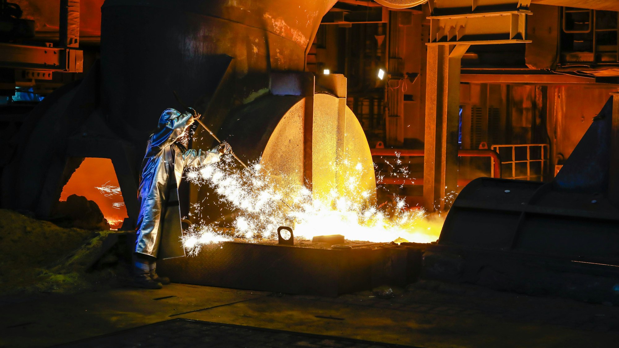 Ein Stahlarbeiter im Schutzanzug entnimmt eine 1500 Grad heisse Roheisenprobe beim Abstich am Hochofen 8 beiThyssenkrupp