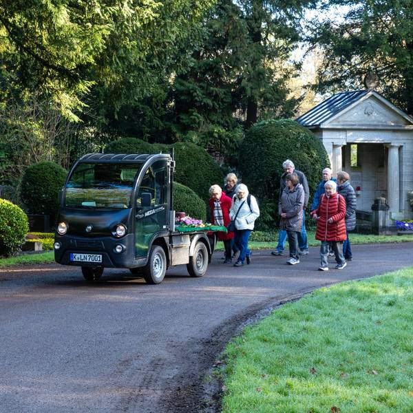 Eine kleine Begleitergruppe folgt auf dem Südfriedhof dem Elektromobil mit der Urne.Vorneweg geht Pfarrer Johannes Krautkrämer.