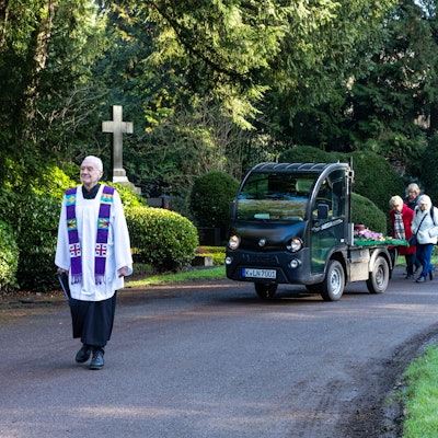 Eine kleine Begleitergruppe folgt auf dem Südfriedhof dem Elektromobil mit der Urne.Vorneweg geht Pfarrer Johannes Krautkrämer.