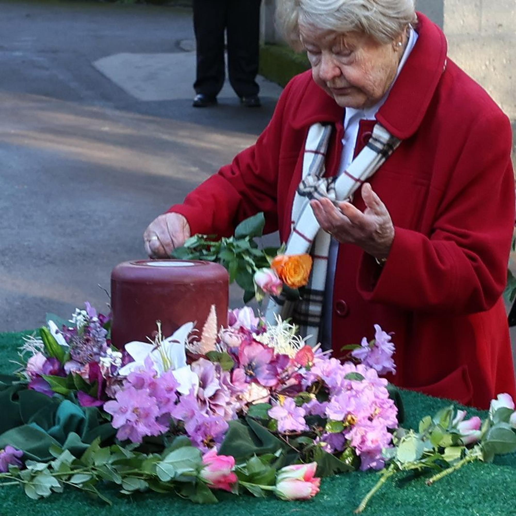 Jeder Trauerzugteilnehmer legt eine Rose an der Urne ab.