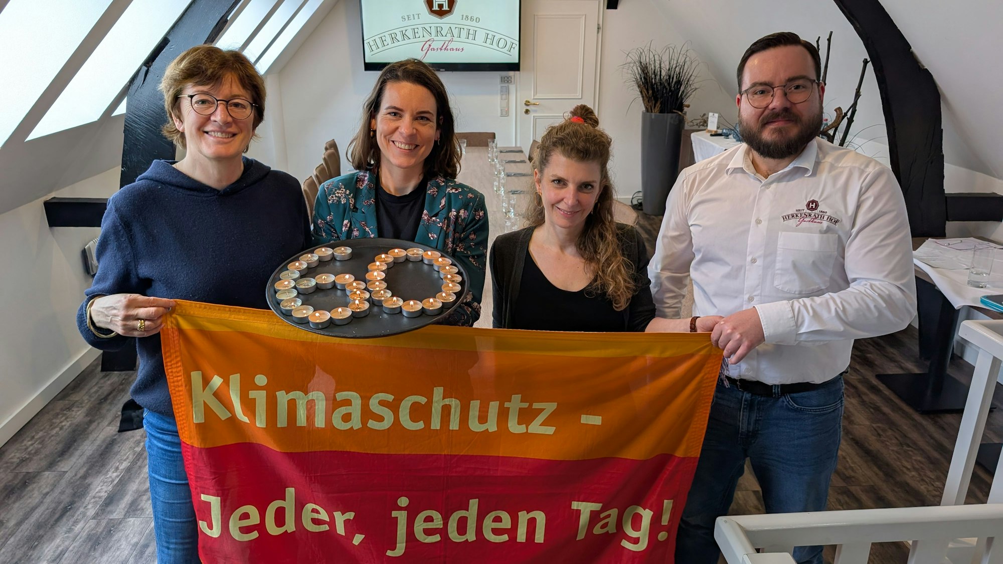 Drei Frauen und ein Mann halten ein Klimaschutztransparent.