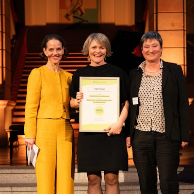 Drei Frauen lächeln in die Kamera, Inga Feuser (Mitte) hält eine Urkunde in den Händen.