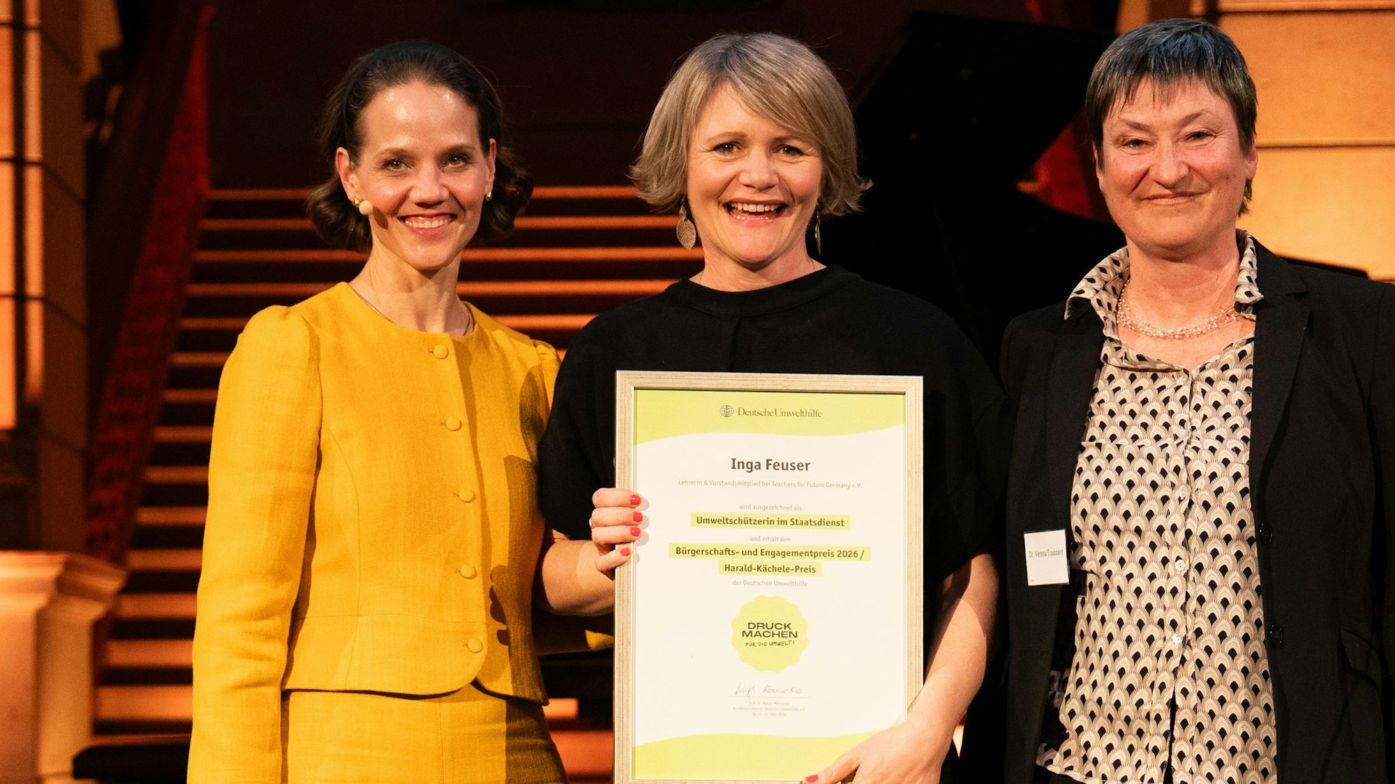 Drei Frauen lächeln in die Kamera, in der MItte steht Inga Feuser.