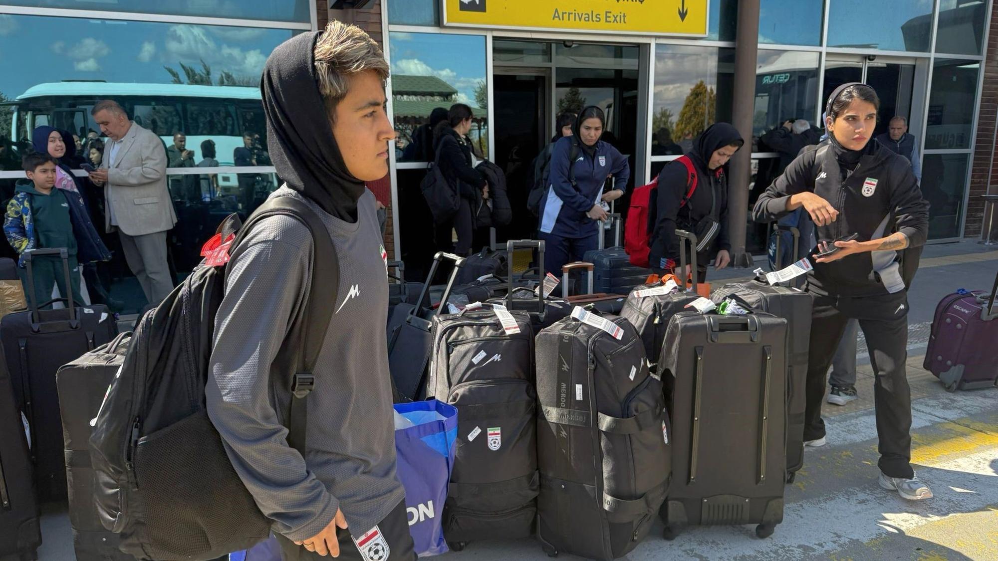 Mitglieder der iranischen Frauenfußballmannschaft stehen bei ihrer Ankunft am Flughafen Igdir in der Osttürkei neben ihren Koffern.