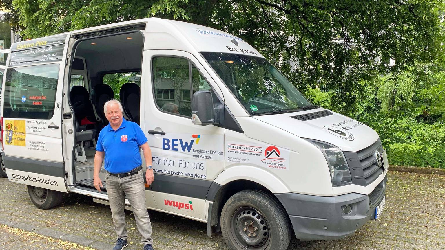 Ein Mann steht vor dem grauen Bürgerbus.