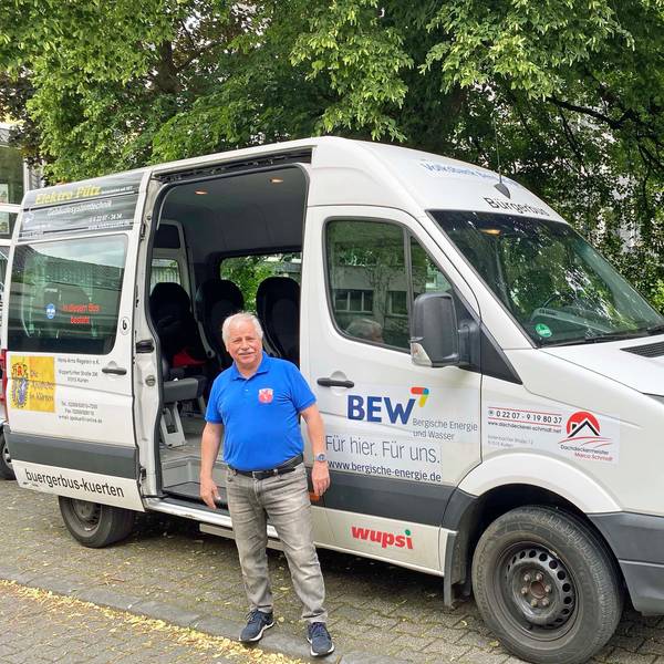 Ein Mann steht vor dem grauen Bürgerbus.