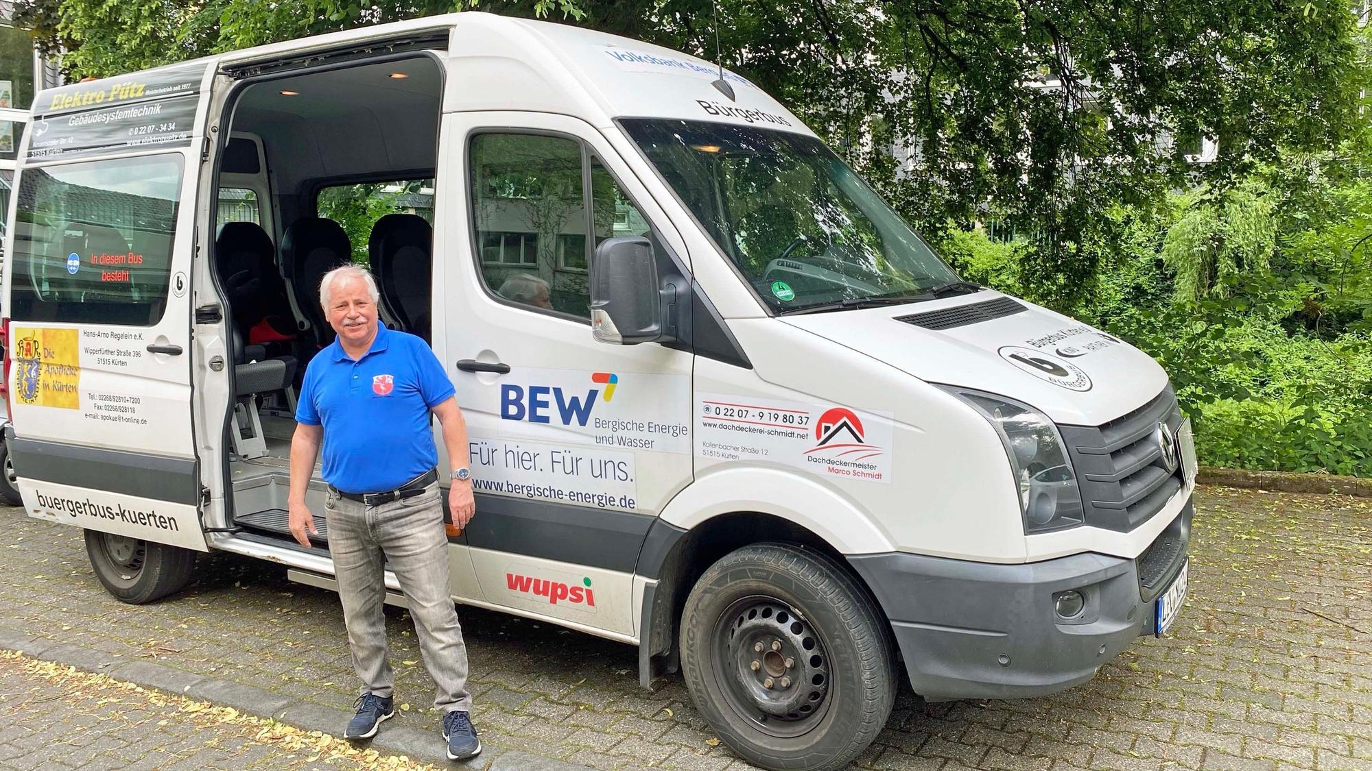 Ein Mann steht vor dem grauen Bürgerbus.