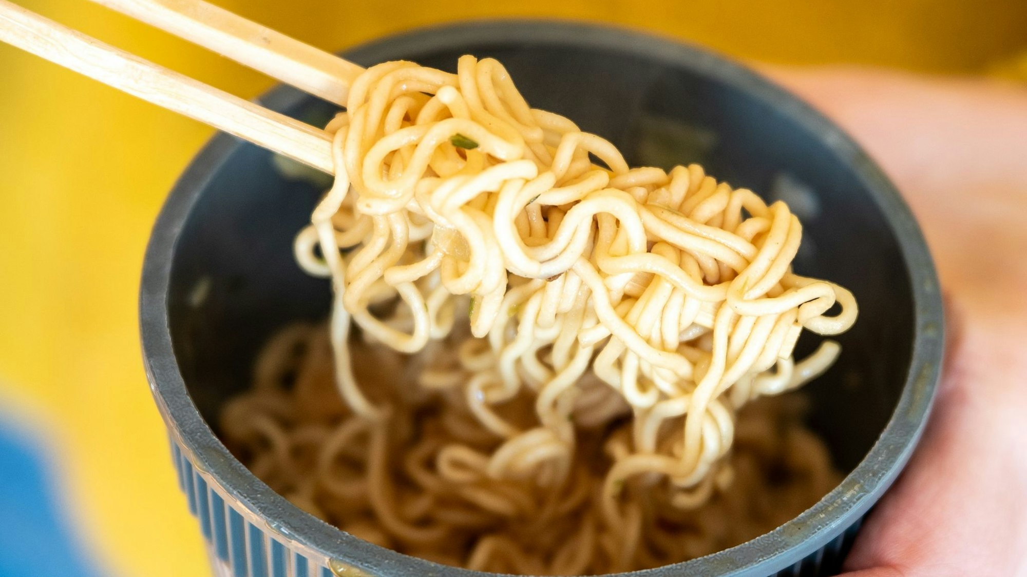 Eine Frau hält einen Becher Instantnudeln in der Hand